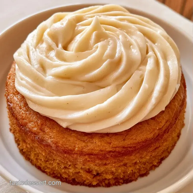 A single slice of moist brown cake with a thick layer of smooth white frosting on a gold-rimmed plate.