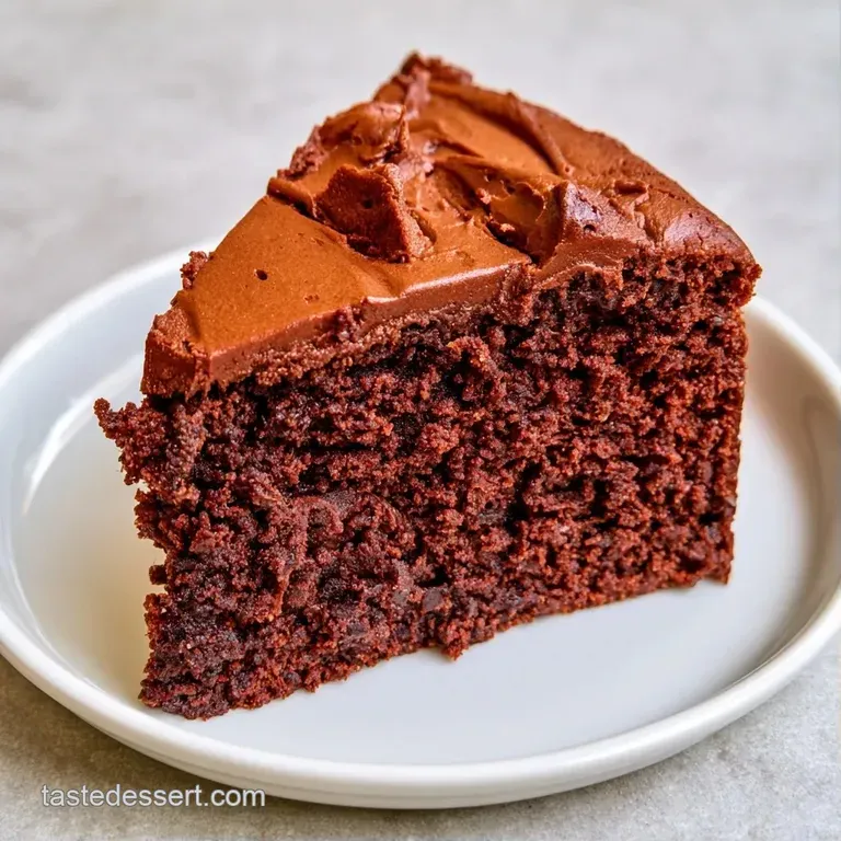A dark chocolate cake wedge paired with a swirl of whipped cream and a single bright red raspberry on a slate board.